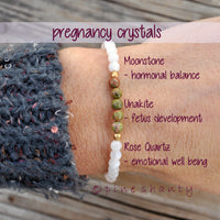 Beaded bracelet on a wrist with pregnancy crystal information